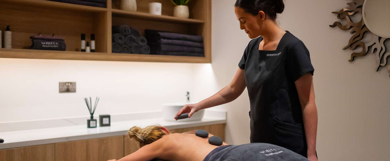 Spa therapist giving a hot stone massage 