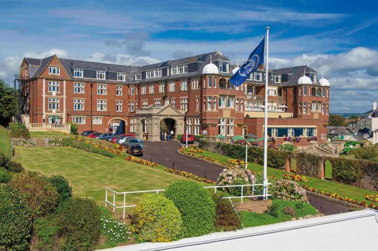 Victoria Hotel External View with Flag and Gardens