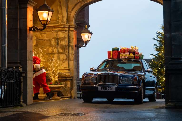 Detail of Santa walking into hotel and Rolls Royce with Gifts on Roof