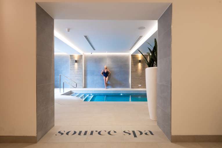 Woman leaning against wall near indoor pool