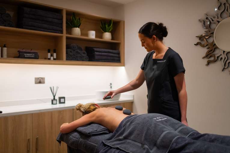 Spa therapist giving a hot stone massage 